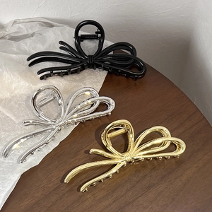 Detailed view of elegant bow-shaped metal hair claws in black, silver, and gold finishes