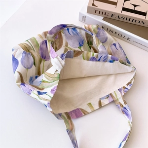 Detailed top view of a canvas tote bag featuring purple tulip floral print and magazines