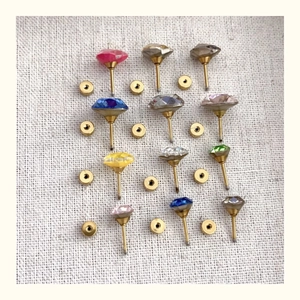 Detailed close-up of multi-colored crystal stud earrings with golden titanium screw backs