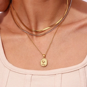 Close-up of triple layered 18K gold plated necklaces featuring snake and rose relief charm