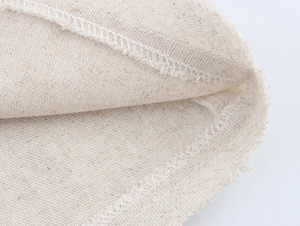 Detailed close-up of beige linen fabric texture and white overlock stitching craft