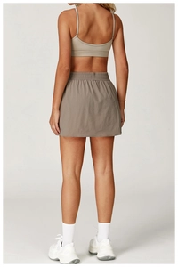 Dettaglio del reggiseno sportivo kaki e della gonna da tennis a pieghe taupe