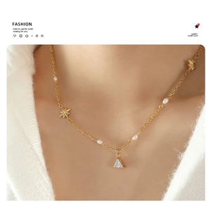 Close-up of gold chain necklace with white pearls, star charms and triangle zircon pendant
