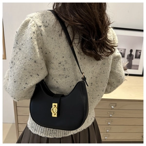 Gros plan d'un sac hobo noir avec fermoir doré vintage porté à l'épaule par un mannequin