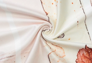 Detail shot of soft beige fabric with abstract orange and brown patterns and smooth texture