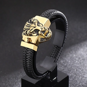 Détail d'un bracelet tressé en cuir noir avec un fermoir tête de lion en acier doré