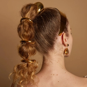 Golden stainless steel ponytail cuffs and teardrop earrings set on a female model