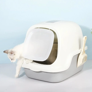 Detail of grey cat litter scoop hanging on a white and grey enclosed litter box