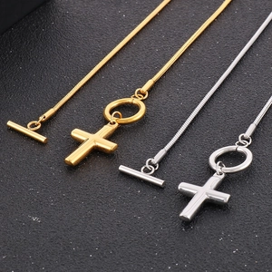 Detail showing gold and silver cross pendants with OT buckle snake bone chains on black texture
