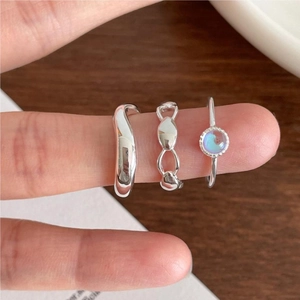 925 silver ring set with wave band, chain design and round gemstone on a wooden surface