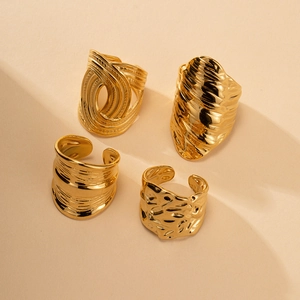 Close-up showing four gold-plated titanium rings with hammered and pleated textures