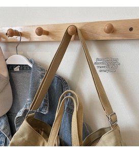 Detail view of khaki canvas tote with adjustable woven strap and metal buckle
