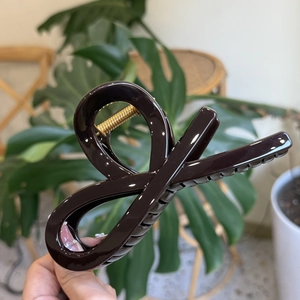 Detail showing a large dark brown resin hair claw clip with a strong gold metal spring