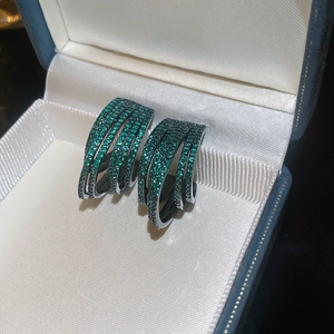 Macro shot of emerald green multi-layer C-shape hoop earrings inside a jewelry box
