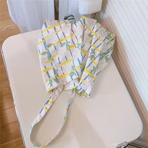 Detail view of a floral cotton tote bag with yellow stripes on a white metal tray