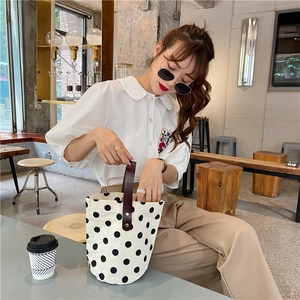 French vintage polka dot bucket bag shown in a cafe setting with a stylish model