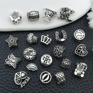 Detailed view of silver alloy beads with clover, crown and owl shapes for DIY jewelry