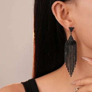 Gros plan d'élégantes boucles d'oreilles à pompons noirs avec strass sur un mannequin