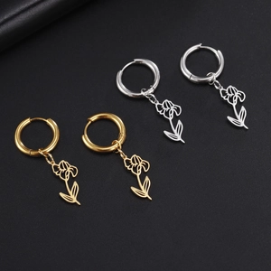 Detailed macro view of gold and silver hollowed floral hoop earrings on dark texture