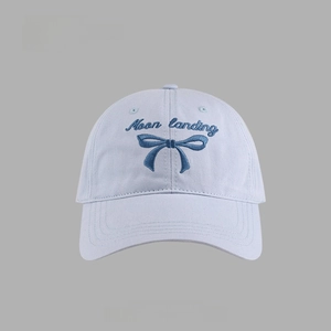 Close-up of blue baseball cap featuring navy bow embroidery and Moon landing text detail