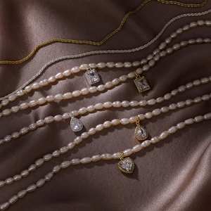 Baroque rice pearl necklace with geometric zircon pendants on luxury brown silk fabric