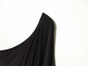 Detail of black knitted mini dress showing asymmetric cut and fabric texture