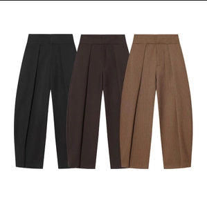 Detail of high-waisted pleated balloon trousers in black, dark brown, and striped brown
