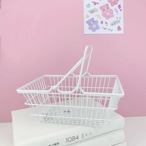 Close-up of a white iron wire basket with double handles on a pink background