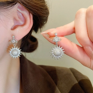 Macro shot of silver drop earrings featuring celestial star, planet and sun crystal designs