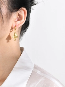 Macro detail of gold mushroom drop earrings with embossed polka dots on a model