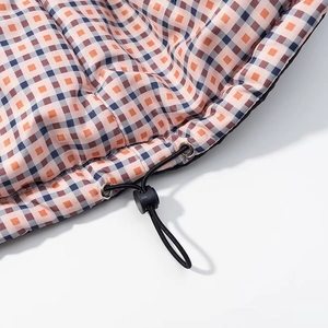 Detail of orange and blue plaid quilted fabric featuring a functional black drawstring