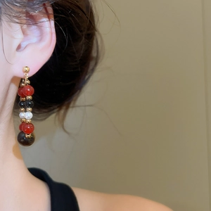 Detail of vintage long beaded tassel earrings with red black beads on a model