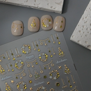 Détail macro de stickers d'ongles de Noël 5D dorés avec motifs sapins et étoiles