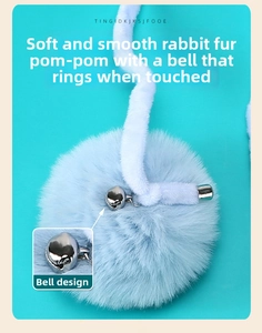 Detail of soft blue rabbit fur pompom cat toy featuring a silver bell and hanging rope