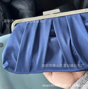 Detail of navy pleated satin evening clutch bag with sparkling diamond-encrusted clasp
