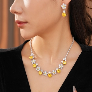 Detail of flower necklace and earrings set with yellow zircon on a female model