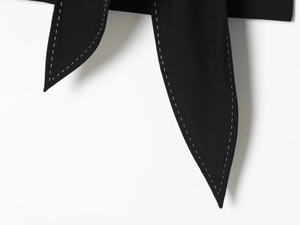 Detailed close-up of black fabric with decorative white contrast stitching on slim dress