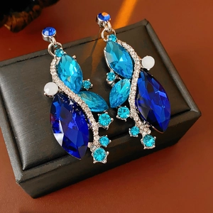 Detailed close-up of vintage blue rhinestone earrings on a black jewelry display case