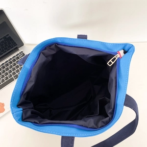 Top view of blue canvas tote bag showing zipper closure and spacious inner lining detail
