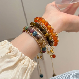 Three-piece tiger eye and faux stone beaded bracelet set worn on model's wrist