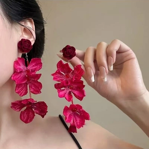 Elegant red fabric flower drop earrings with a vintage velvet finish on female model