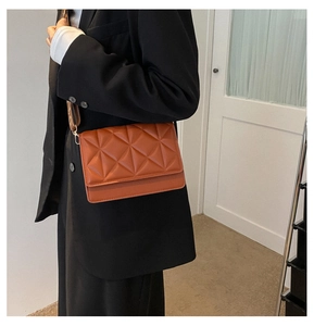 Detailed view of brown quilted leather handbag featuring wide shoulder strap and flap