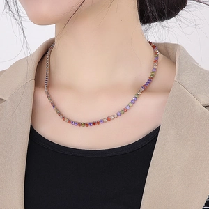 Close-up of a rainbow tennis necklace with gradient square gemstones on a model