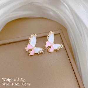 Macro shot of pink butterfly stud earrings with sparkling cubic zirconia in gold plating