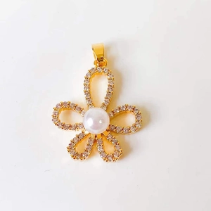 Close-up of a gold flower pendant featuring a central pearl and diamond-encrusted petals