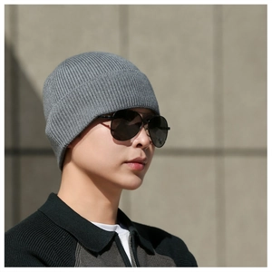 Détail d'un bonnet en maille côtelée gris foncé avec lunettes de soleil en décor hiver