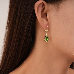 Vintage green teardrop crystal earrings with gold trim on a fashion model profile