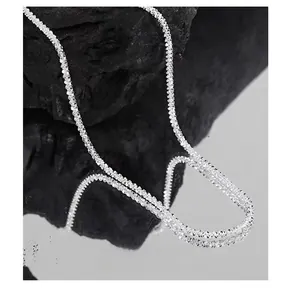 Macro shot of sparkling 925 sterling silver chain draped over a black mineral stone