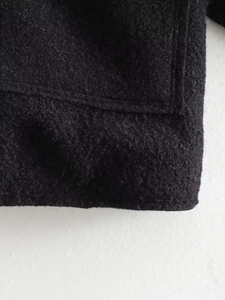 Close-up of high-quality black wool fabric texture and stitching on the jacket sleeve