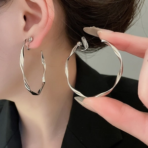 Close-up of silver twisted round clip-on earrings featuring a glossy metallic finish